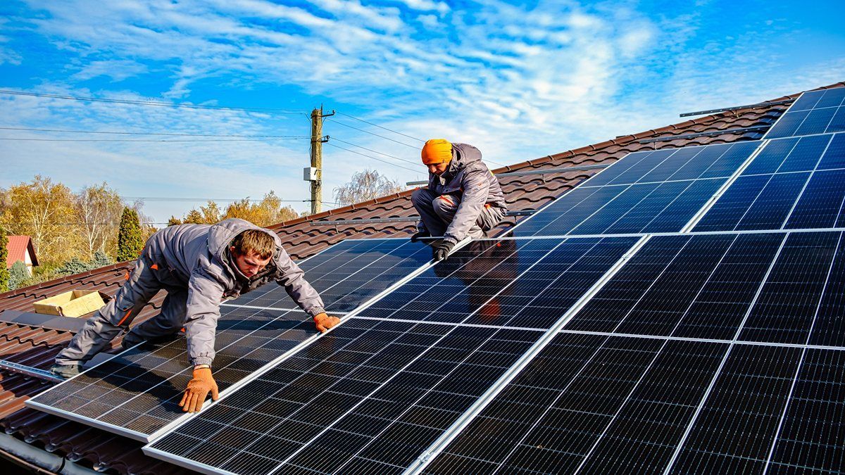 Técnicos de O&G instalando paneles solares sobre un techo de teja